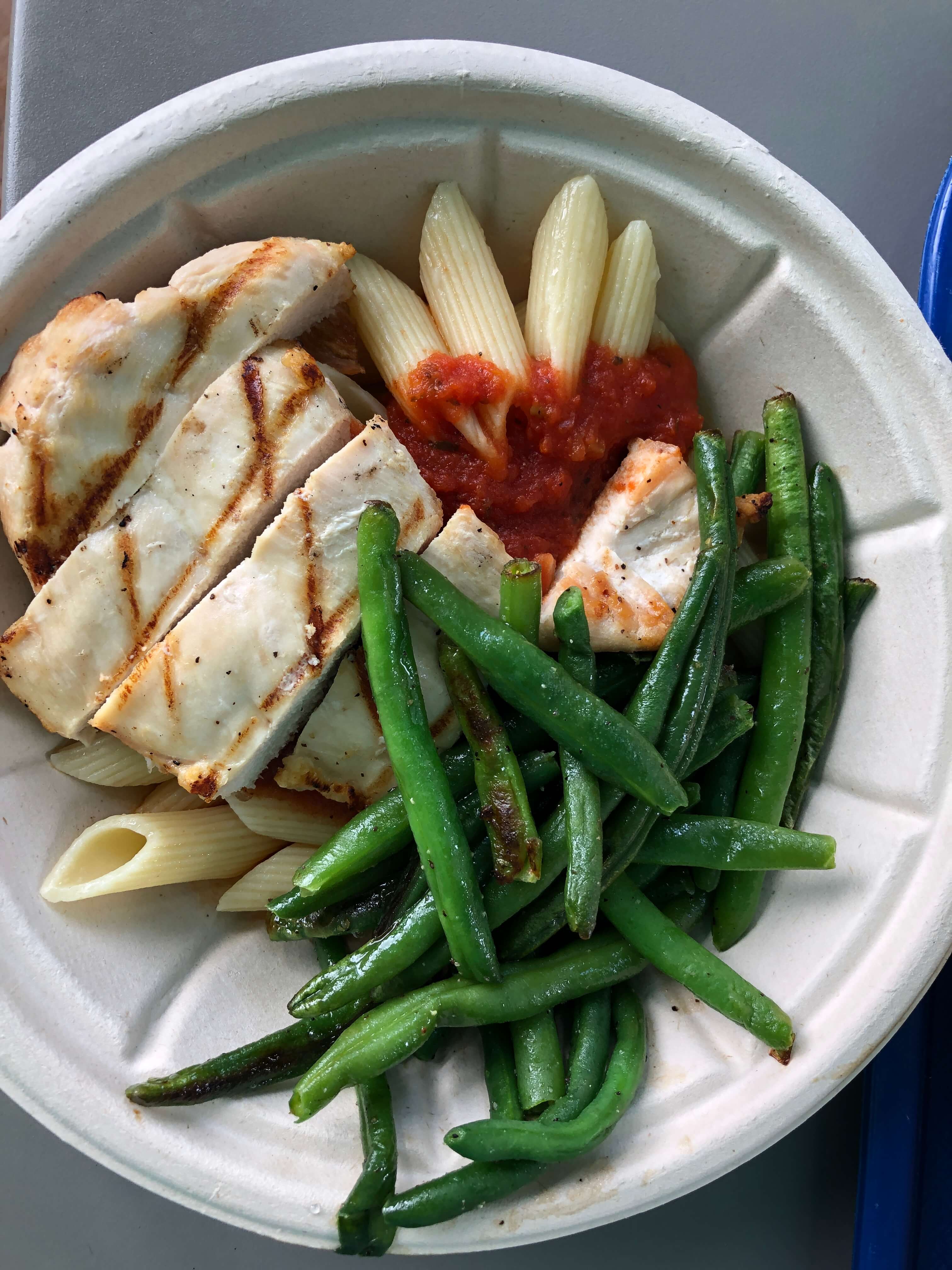 a close-up view of a kids meal featuring grilled chicken, green beans, and pasta with marinara
