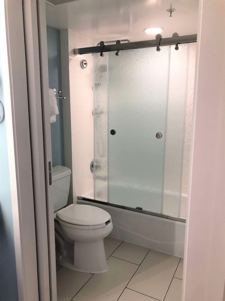 a shower with sliding glass doors and a toilet in a bathroom with a pocket door