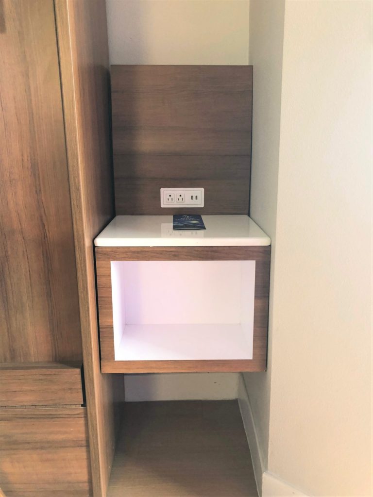 a cubby with two USB ports and two outlets serves as a bedside table