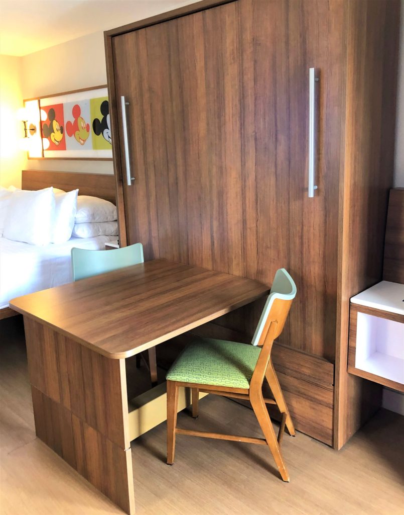 a murphy bed is folded into the wall and serves as a desk with two chairs
