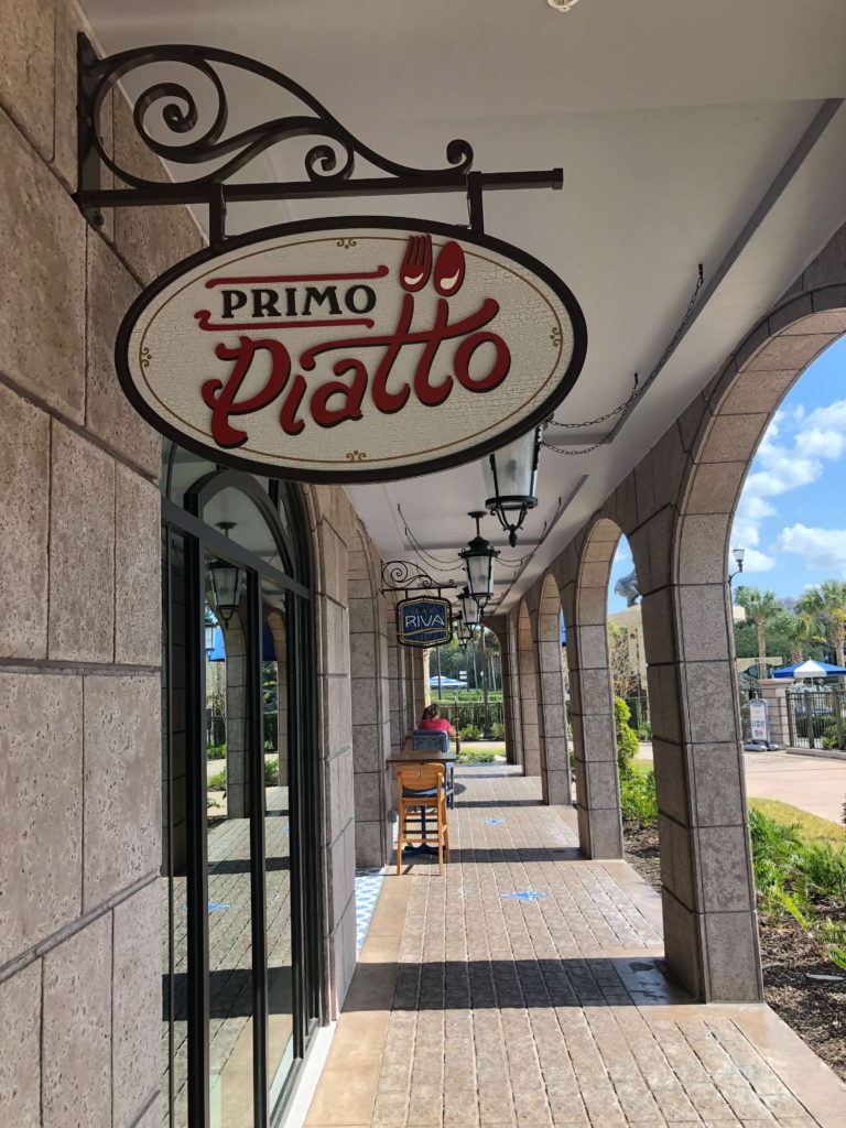 a sign for Primo Piatto, with a fork and spoon styled into the Ts, hangs by the entrance