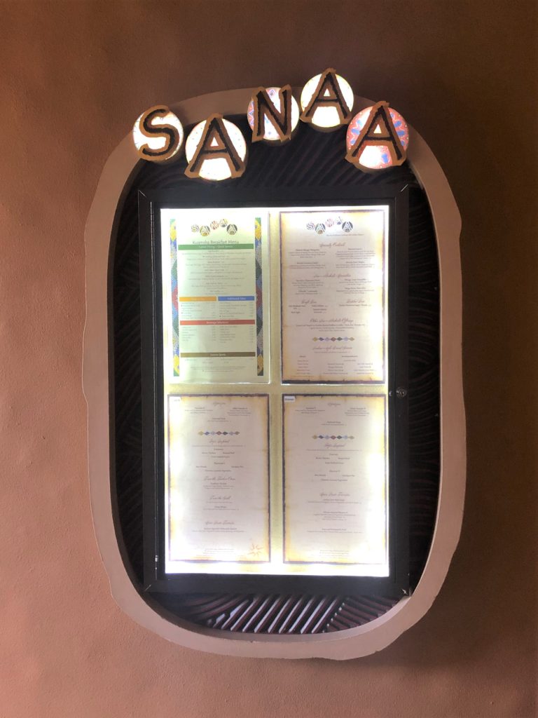 Sanaa's full menu, backlit, hangs framed outside the restaurant