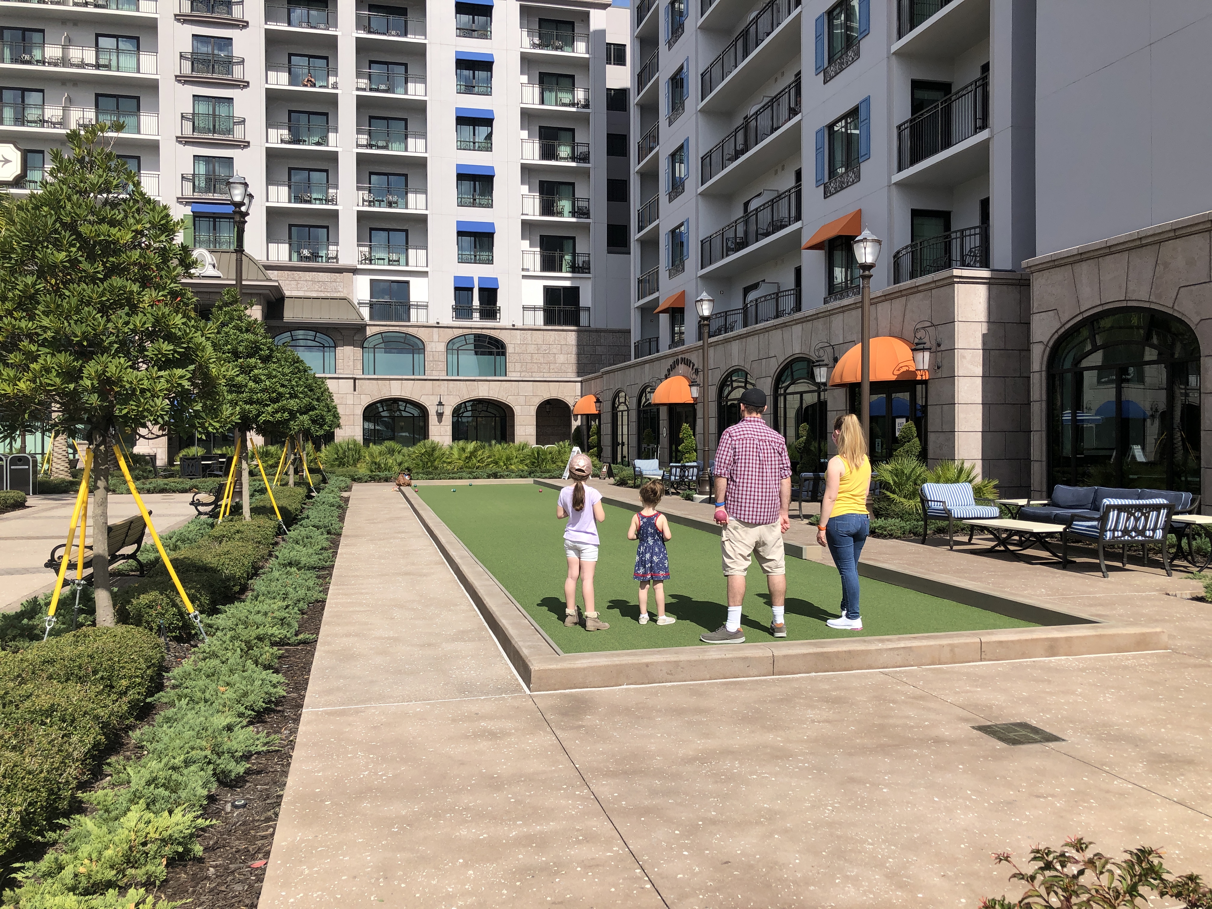 a family of four plays bocce ball on a manicured lawn