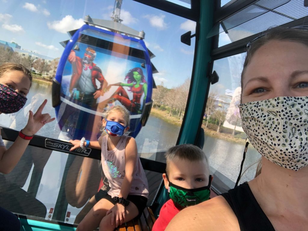 a family of four takes a selfie from a gondola as another gondola passes behind them
