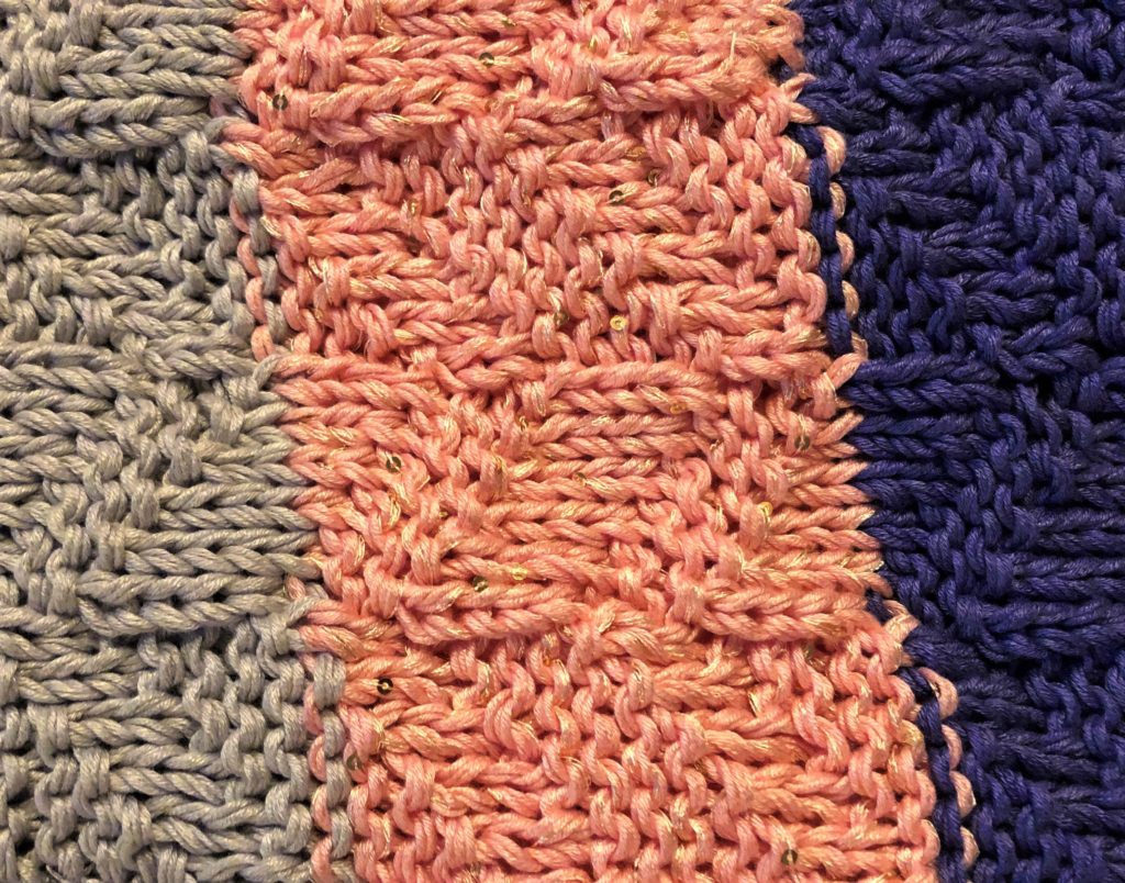 a close-up of a textured knitting stitch on a baby blanket reveals sequins throughout the stitching