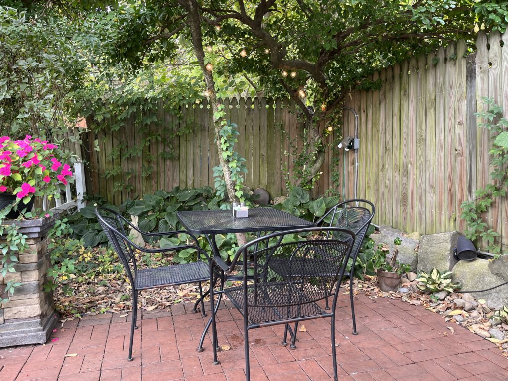 an empty wrought-iron table waits for diners by ivy-covered fences at The Secret Garden Café