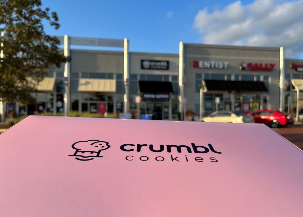 a large pink box labeled "Crumbl Cookies" features a smiling chef logo