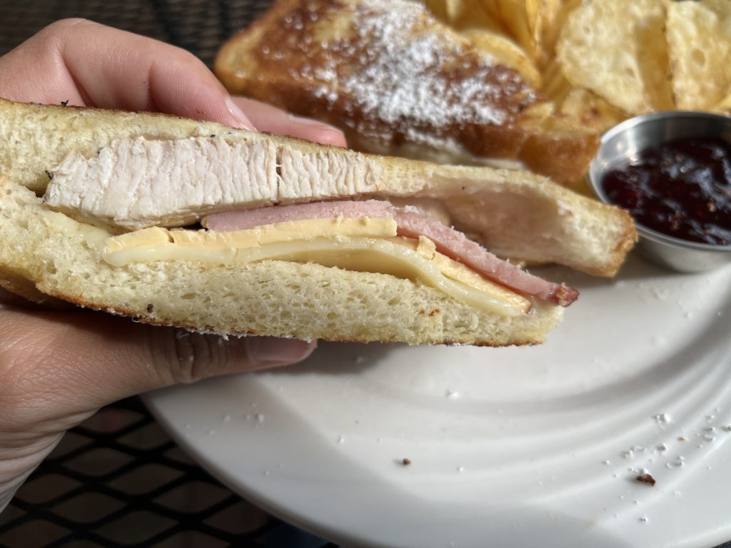 a close-up of a turkey, ham, and gouda sandwich at The Secret Garden Café