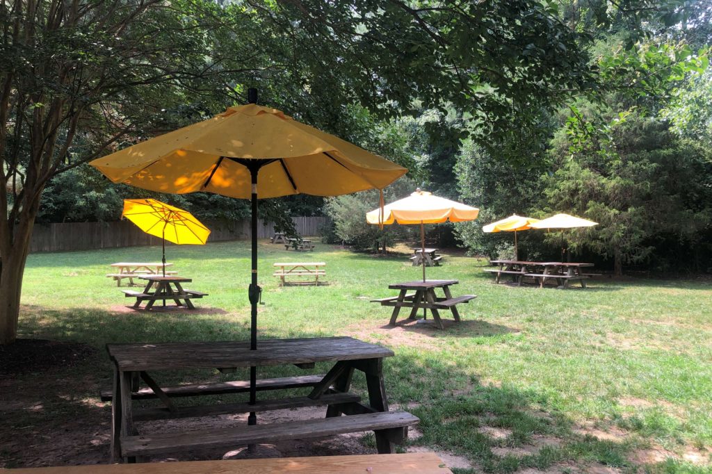 dozens of picnic tables with umbrellas line the field at Pierce's Pitt Bar-B-Que