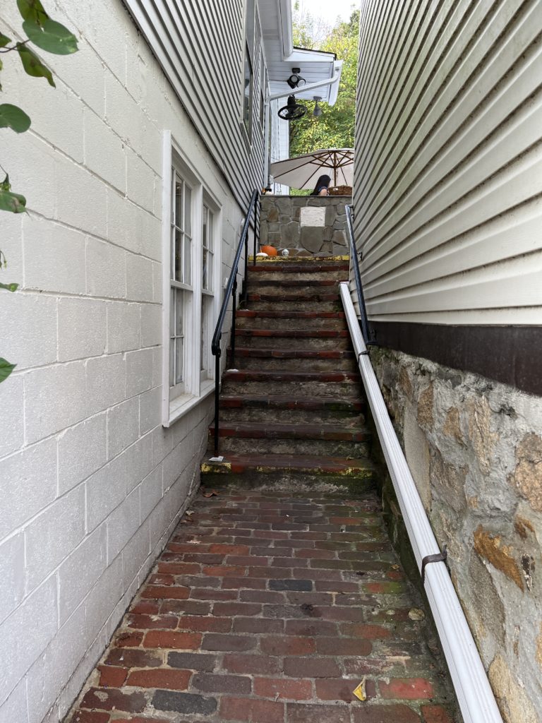 a narrow alley leads up brick steps to a hostess stand at The Secret Garden Café