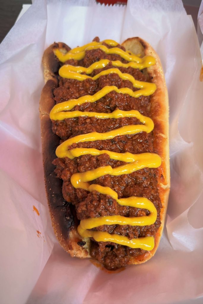 a hot dog covered in chili and zig-zagged with mustard