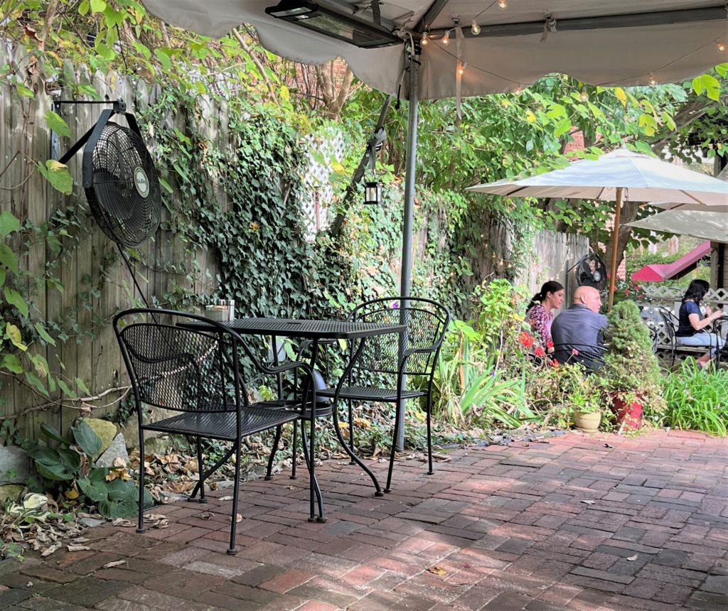 an empty wrought-iron table waits for diners by ivy-covered fences at The Secret Garden Café
