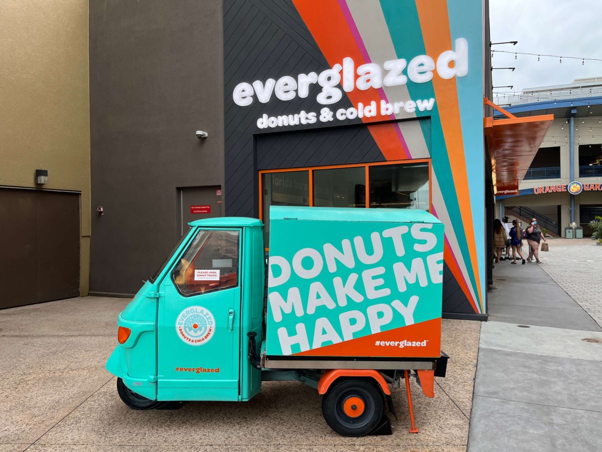 A miniature truck reads "Donuts Make Me Happy" by the exterior of Everglazed Donuts & Cold Brew at Disney Springs