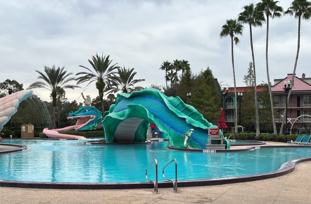 a water slide shaped like a giant serpent with Triton on his back looks like he's dipping in and out of a large pool
