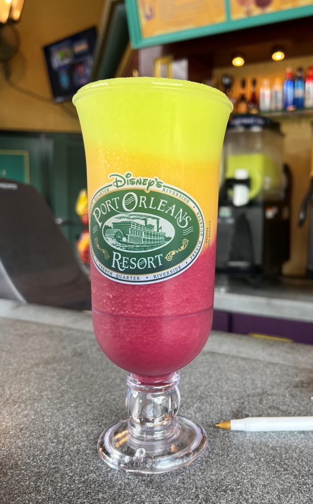 a frozen drink with three colorful layers in a hurricane glass