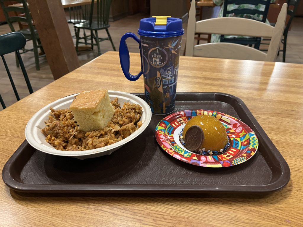 a plate of jambalaya and cornbread, dessert, and a 50th anniversary cup at Riverside Mill and Market at Disney's Port Orleans Riverside Resort