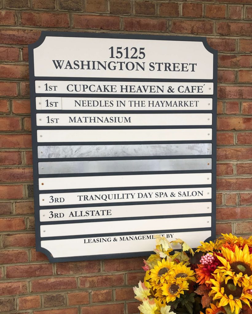 a sign for 15125 Washington Street showing Needles in the Haymarket is located on the first floor of the building