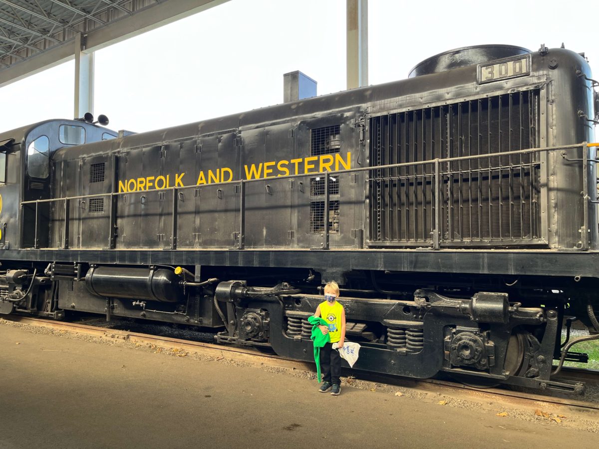 a young boy poses beside a Norfolk and Western train at the Virginia Museum of Transportation