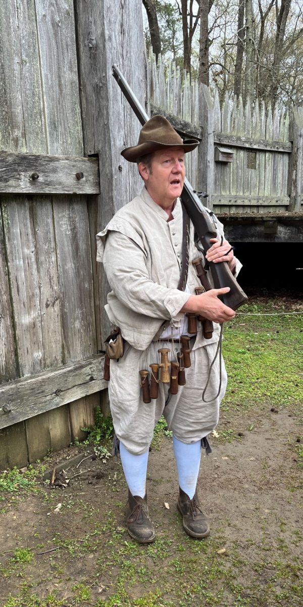 a historical interpreter holds a musket at Jamestown Settlement