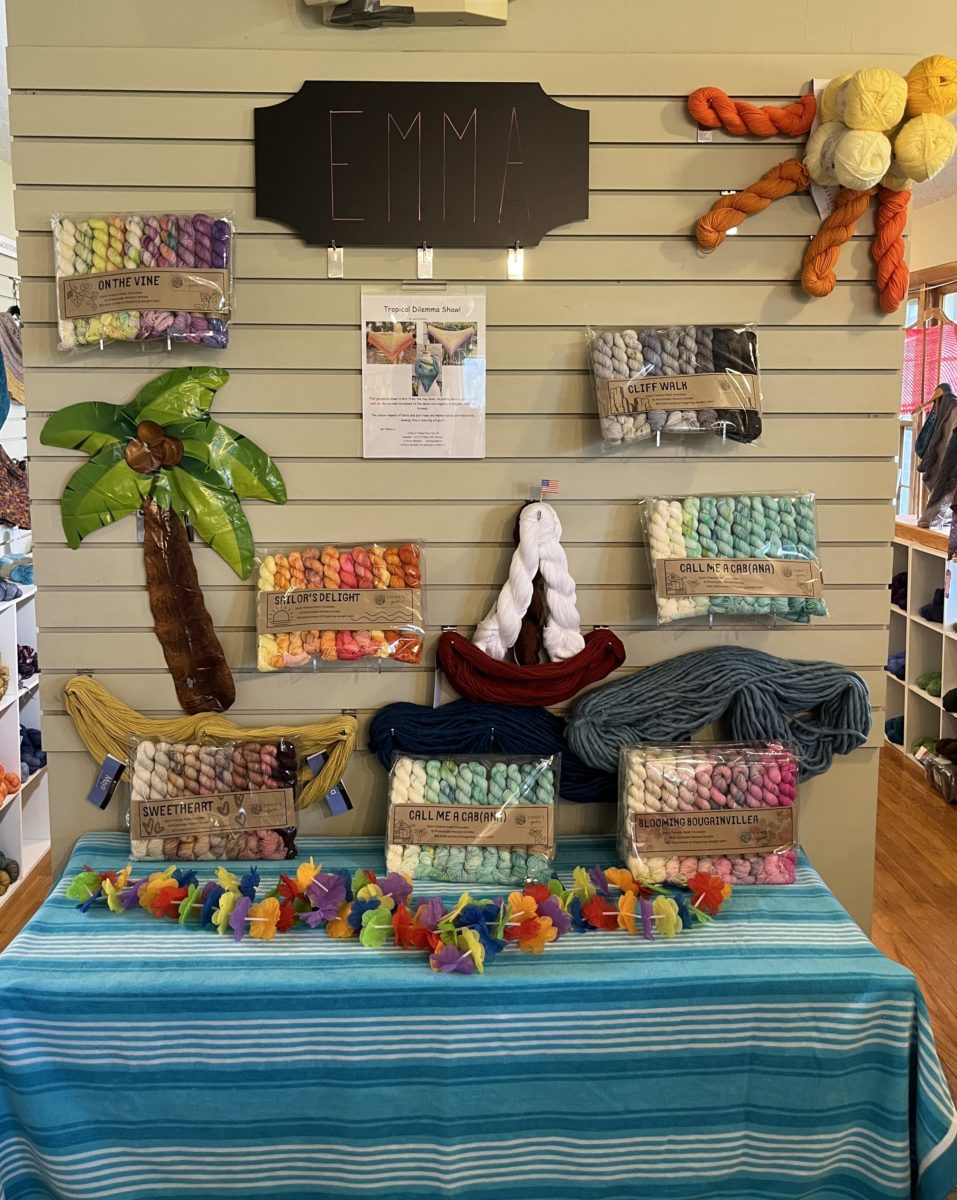 a beach display crafted out of whole skeins of yarn, styled as sand, waves, sailboats, and sunshine