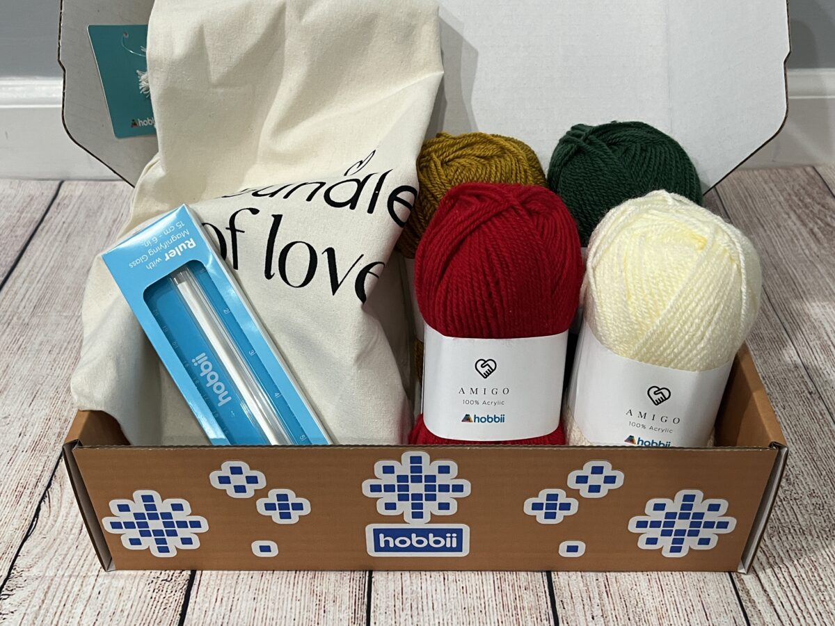 Hobbii Yarn Advent Calendar for Knitters box for week 1: opened, containing yarn, ruler, project bag