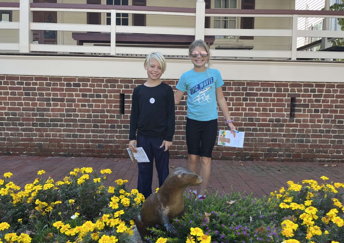 children pose with bronze otter statues in Fredericksburg, Virginia (Otterly Amazing Scavenger Hunt)