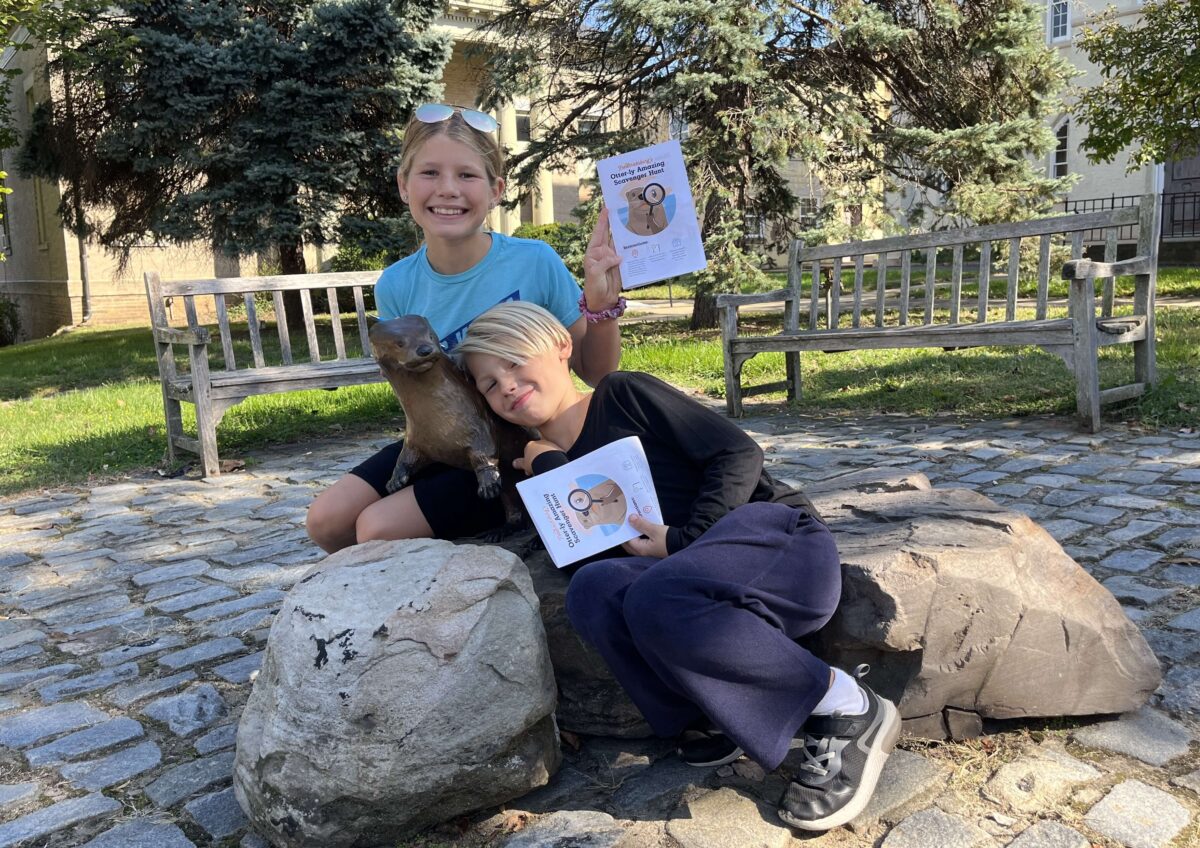 children pose with bronze otter statues in Fredericksburg, Virginia (Otterly Amazing Scavenger Hunt)