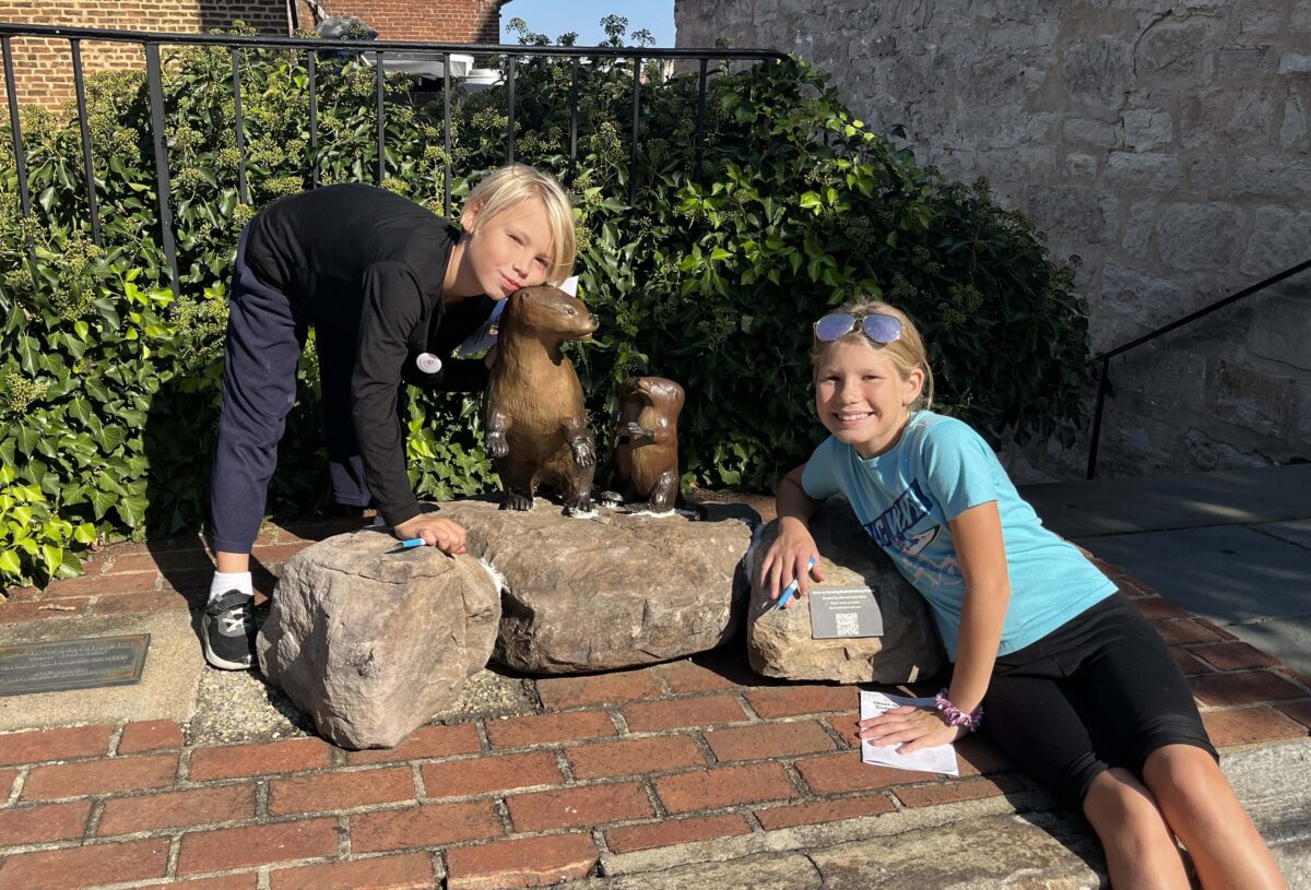 children pose with bronze otter statues in Fredericksburg, Virginia (Otterly Amazing Scavenger Hunt)