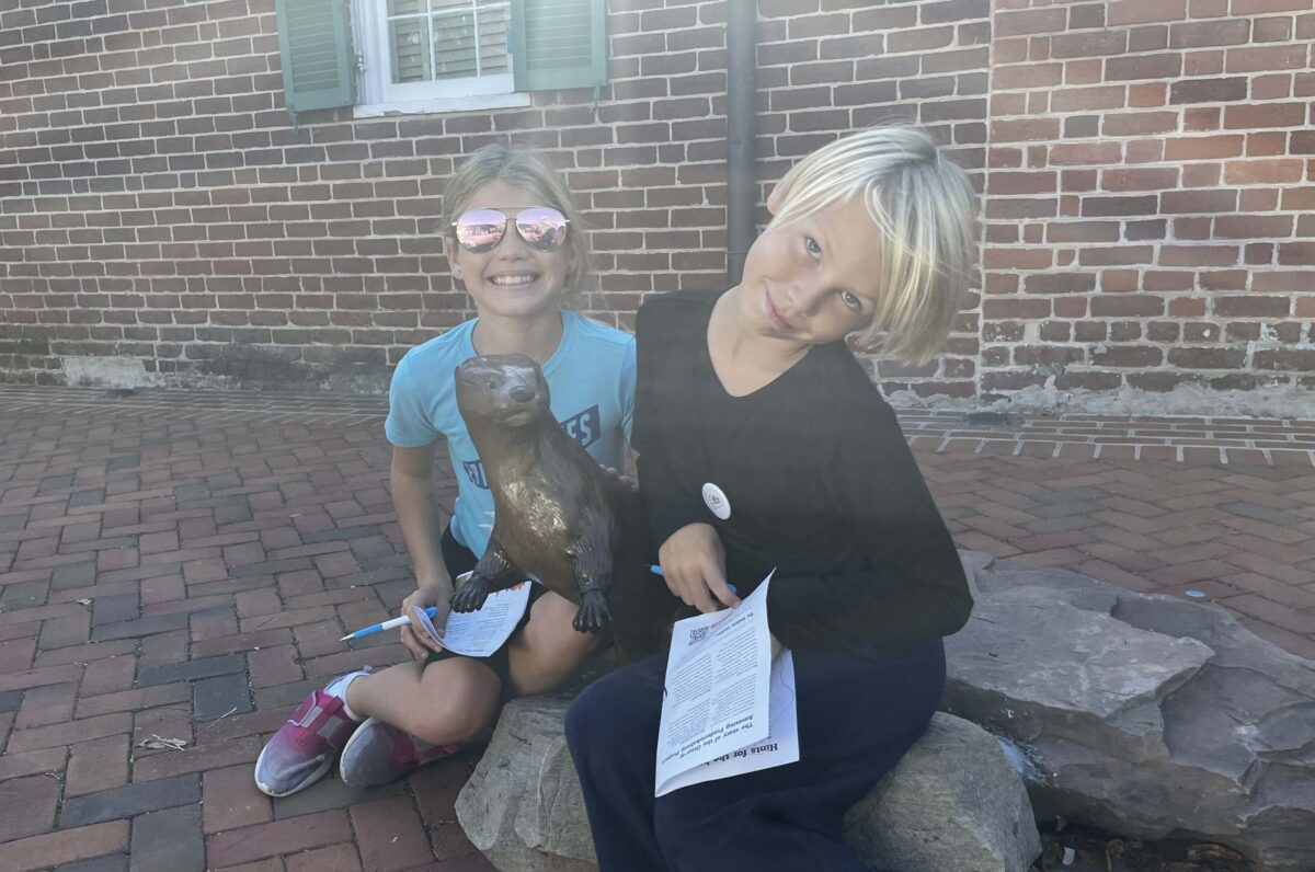 children pose with bronze otter statues in Fredericksburg, Virginia (Otterly Amazing Scavenger Hunt)